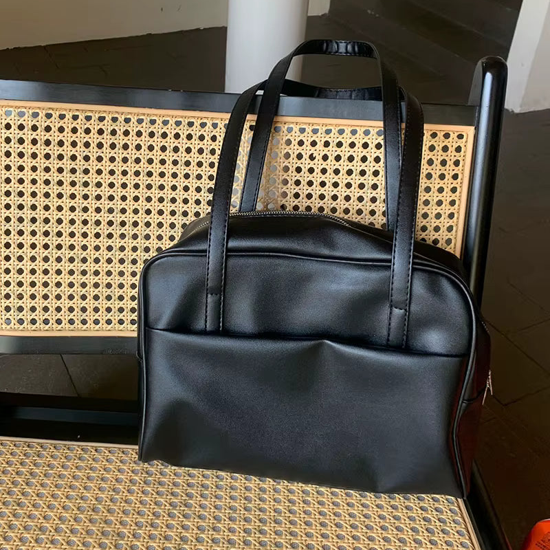 Black leather handbag on a chair with a wicker backrest