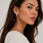 Close-up of a woman wearing diamond earrings with a neutral background